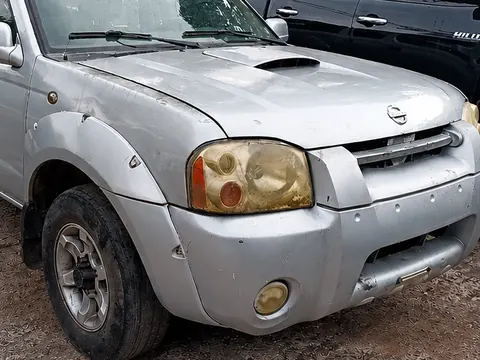Nissan Frontier prata com a frente amassada no pátio